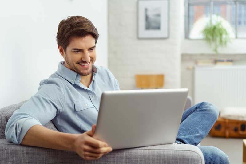 man smiling while using a laptop